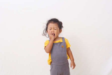 Adorable asian girl standing while showed a screaming expression, close her eyes. Isolated on white backgroundの写真素材