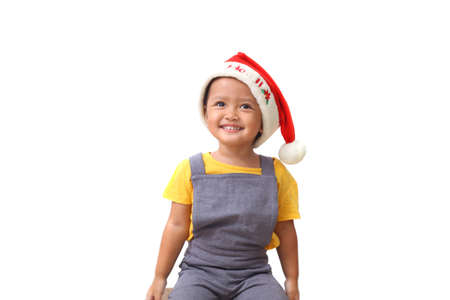 Adorable asian little girl sitting while wearing santa's hat. Christmas kids concept. Isolated on white backgroundの写真素材