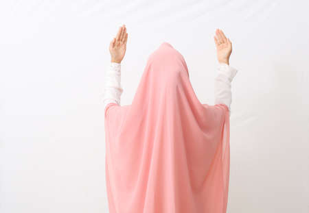 Back view of a muslim woman wearing a veil or hijab praying. Isolated on white background with copy spaceの写真素材