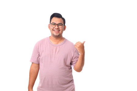 Portrait of happy asian male wearing glasses and purple shirt standing while pointing or presenting something beside him. Isolated on whiteの写真素材