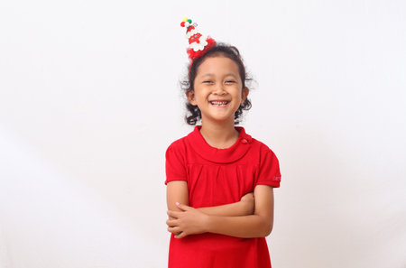 Adorable Asian girl in Christmas costume is standing and smiling. Isolated on white backgroundの写真素材
