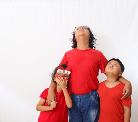 Adorable Asian kids in red shirt is standing and celebrating christmas. Isolated on white background