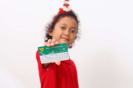 Yogyakarta, Indonesia - Dec 18, 2020 : Adorable Asian girl holds "Kartu Indonesia Sehat (KIS)" or card for health insurance for Indonesian residentsのeditorial素材