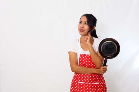 Portrait of asian woman wearing kitchen apron while holding a cooking utensil. Isolated on white backgroundの写真素材
