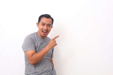 Portrait of asian man pointing something on empty space. Isolated on white with copyspaceの写真素材