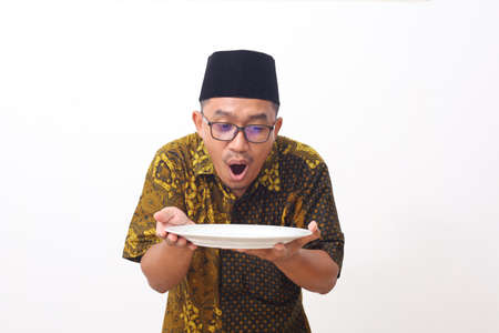 Wow and shocked face of Asian man point to present an empty plate. Isolated on white background