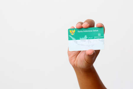 Yogyakarta, Indonesia - Mar 10, 2021 : Hand holds Kartu Indonesia Sehat(KIS) or Indonesia Health Card, Health Insurance card from the Government of Indonesiaのeditorial素材