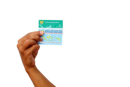 Yogyakarta, Indonesia - Mar 10, 2021 : Hand holds Kartu Indonesia Sehat(KIS) or Indonesia Health Card and Kartu Tanda Penduduk (KTP) or Indonesian Identity Cardのeditorial素材