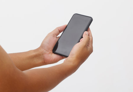 Man's hand holding the black smartphone with blank screen and modern frameless design. Isolated on white background.の写真素材