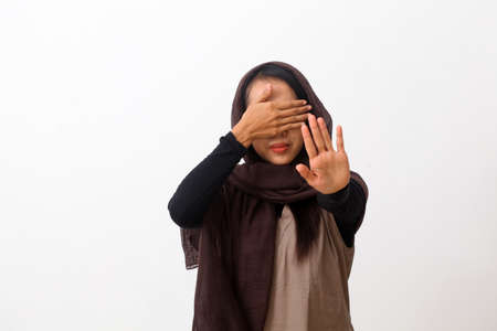 A portrait of asian muslim woman wearing a veil or hijab close her eyes with 'say no' gesture. Isolated on white background with copy spaceの写真素材