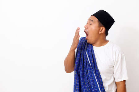 Portrait of funny Asian man yawning and showing a sleepy gesture. Isolated on white backgroundの写真素材