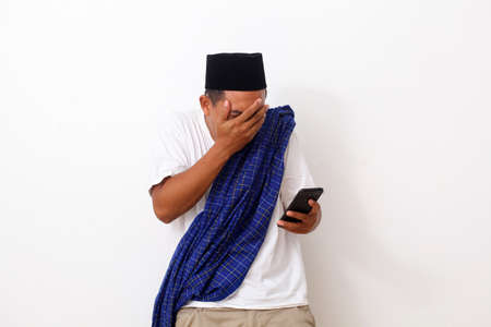 Shocked asian man while looking at his cellular phone. Isolated on white backgroundの写真素材