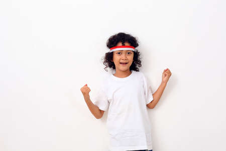 Asian kid with red white headband standing against white background with fist hand gesture. Independence day conceptの写真素材