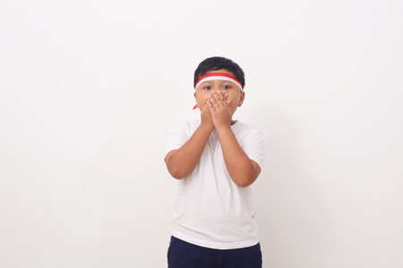 Asian kids with red white headband ribbon standing while cover her mouth. Isolated on white...