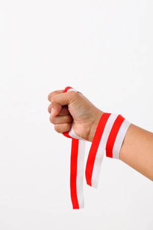 A human hand holds red white ribbon as symbol of the Indonesian flag. Isolated on white backgroundの写真素材