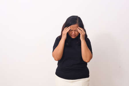 Beautiful asian girl standing while holding her head. headache concept. Isolated on white background with copyspaceの写真素材