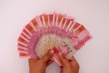 Hand holding Indonesian currency, 100,000 rupiah banknotes with white backgroundの写真素材