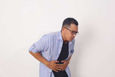 Man putting his hands for belly or stomach ache on white background. Health conceptの写真素材