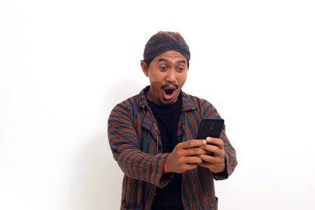 Successful asian man standing while holding a cellular phone and get a good news. Isolated on whiteの写真素材