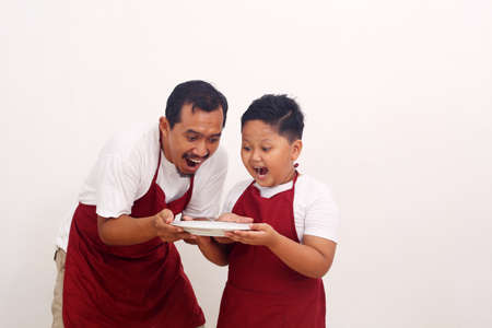 Surprised asian father and son standing while holding a empty plate. Isolated on white backgroundの写真素材