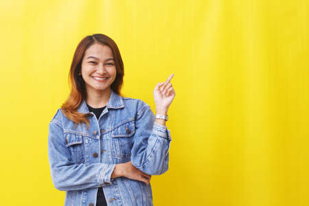 asian woman standing smiling pointing to empty spaceの写真素材