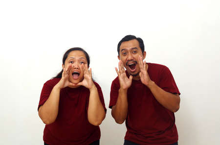 Cheerful asian couple standing while screaming or shouting. Isolated on white with copyspace