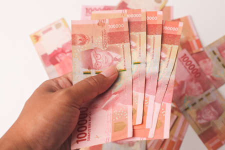 Hand holds Indonesian rupiah cash banknotes money isolated on white