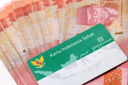 Yogyakarta, Indonesia - June 14, 2022 : Indonesian health insurance card (Kartu KIS BPJS Kesehatan) on Indonesian banknotes moneyのeditorial素材
