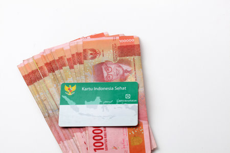 Yogyakarta, Indonesia - June 14, 2022 : Indonesian health insurance card (Kartu KIS BPJS Kesehatan) on Indonesian banknotes moneyのeditorial素材