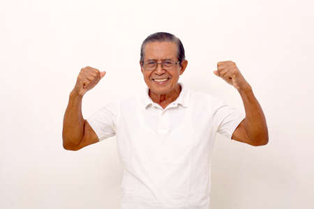 Happy asian old man standing while showing strong gesture. Isolated on white backgroundの写真素材