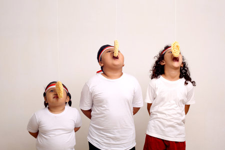 Asian kids celebrating indonesian independence day with cracker eating contest.