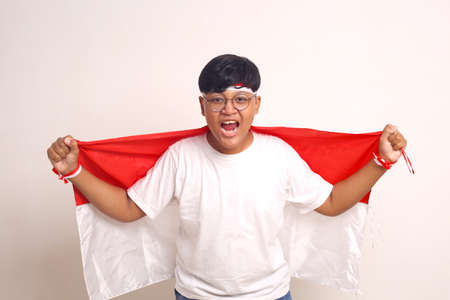 Passionate Asian boy holding indonesian flag and screaming. Indonesian independence day concept