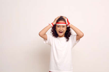 Surprised excited asian girl standing while holding her head. Indonesian independence concept.の写真素材