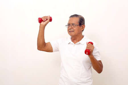 Elderly asian man standing while lifting dumbbells. Isolated on white background.