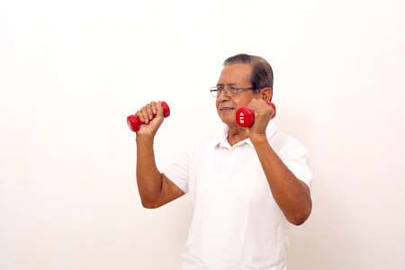 Elderly asian man standing while lifting dumbbells. Isolated on white background.の写真素材