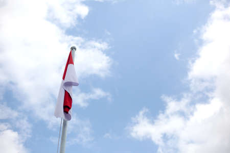Indonesian flag on pole against blue sky