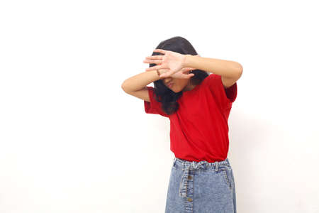 Stressed asian little girl standing while covering her face with hands. Isolated on white