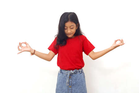 Asian little girl holds hands in yoga gesture relaxing meditating keeping eyes closedの写真素材