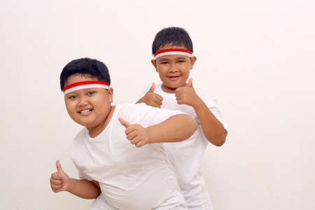 Adorable Asian boys standing while showing thumbs up. Indonesian independence day concept.の写真素材