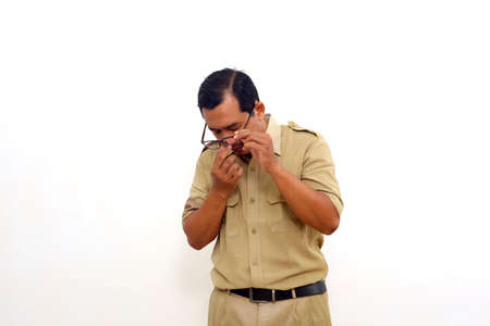 Tired Indonesian government employees standing while take his glasses off. Isolated on whiteの写真素材