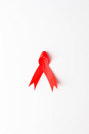 Close up photo of red ribbon over white background with copyspace. Aids day concept