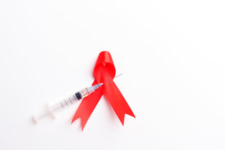 Medical syringe and red ribbon over white background. Aids day conceptの写真素材
