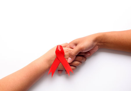 Two hands holds each other with red ribbon. Aids day concept