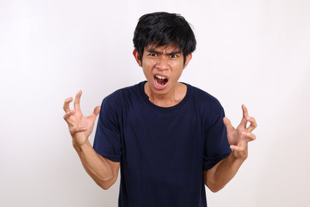 Portrait of asian young man standing with angry expression and gesture. Isolated on white backgroundの写真素材