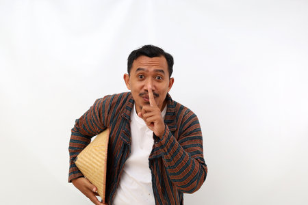 Funny asian farmer standing with telling secret hand gesture. Isolated on white backgroundの写真素材