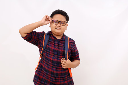 Handsome asian school boy with backpack standing while looking at the camera. Isolated on white backgroundの写真素材