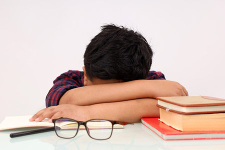 Tired asian school boy sleeping while studying. Isolated on white background