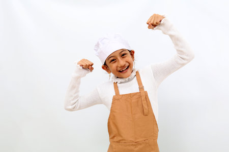 Wow excited expression of little girl in chef uniform lifting her hands. Successful concept. Isolated on white backgroundの写真素材
