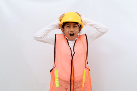 Shocked Asian little girl in the construction helmet as an engineer standing while holding her head....