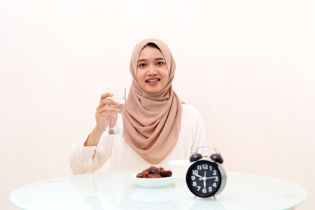 Young asian muslim woman carrying a glass of water for breaking her fasting. Ramadan concept